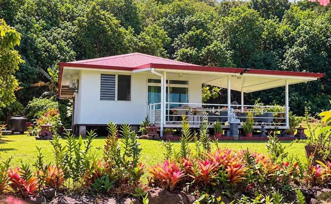 Le bungalow blanc au toit rouge, sa terrasse et son jardin fleuri au pied de la montagne